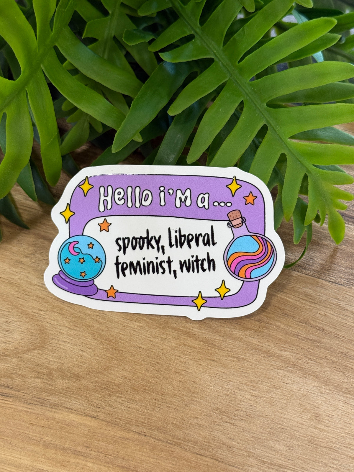 Lavender Hello I'm a spooky liberal feminist witch sticker with stars, a crystal ball, and a colorful potion bottle
