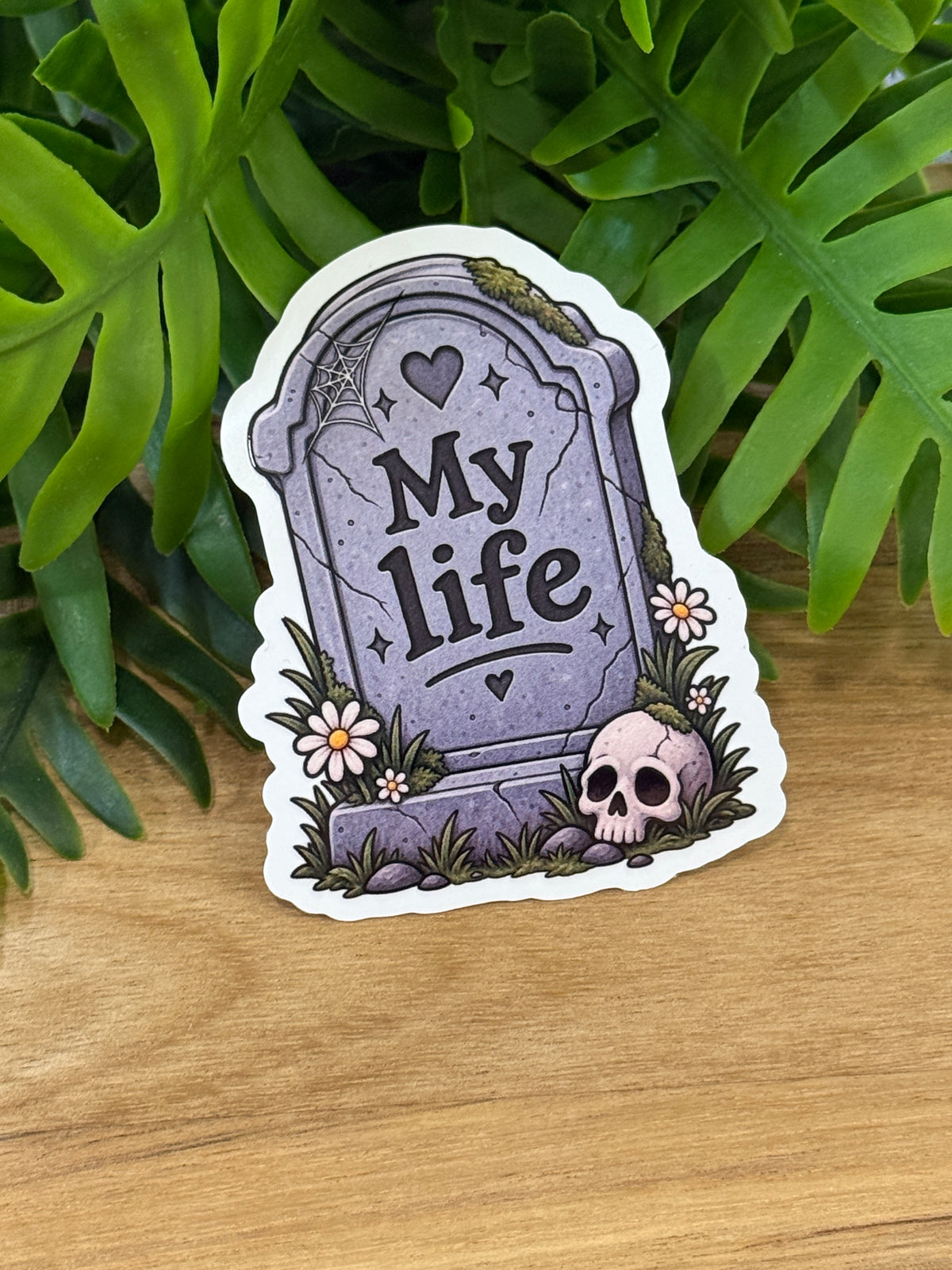Purple-gray tombstone vinyl sticker reading My life with hearts, a cobweb, daisies, moss, and a skull