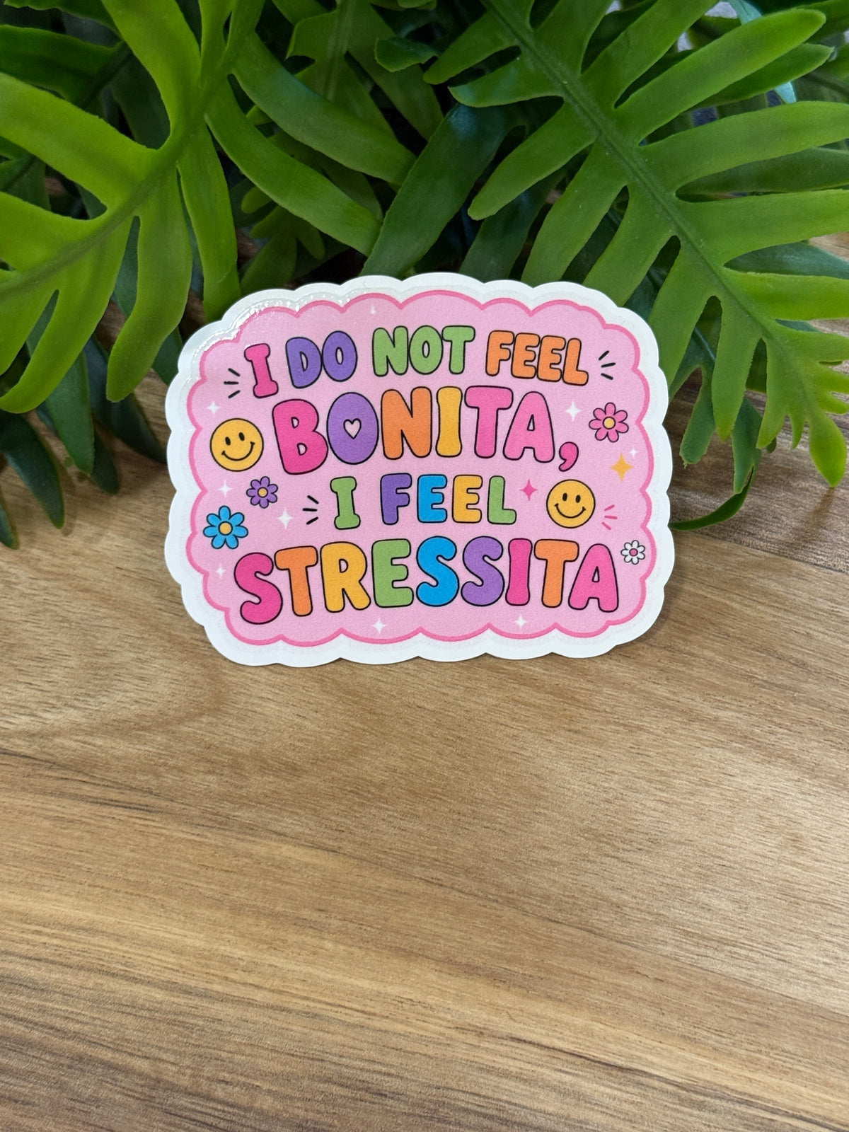 Pink I Do Not Feel Bonita, I Feel Stressita sticker with multicolored lettering, flowers, and smiley faces