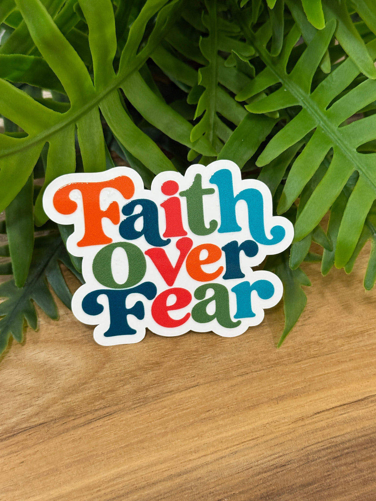 Faith Over Fear sticker with colorful retro lettering in orange, coral, green, and blue and a white border