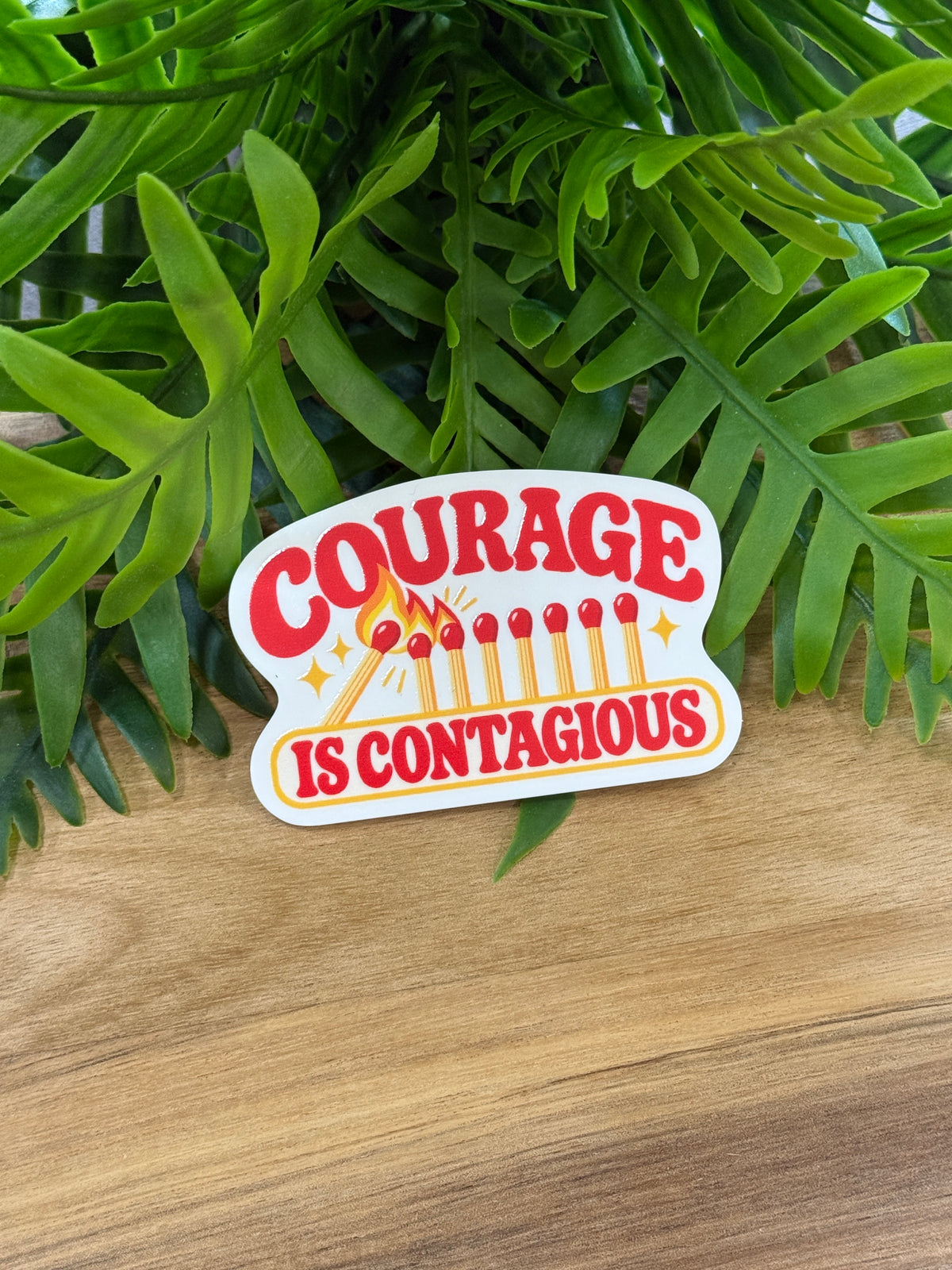 Courage Is Contagious white acrylic magnet with bold red lettering, yellow matches, and flame artwork