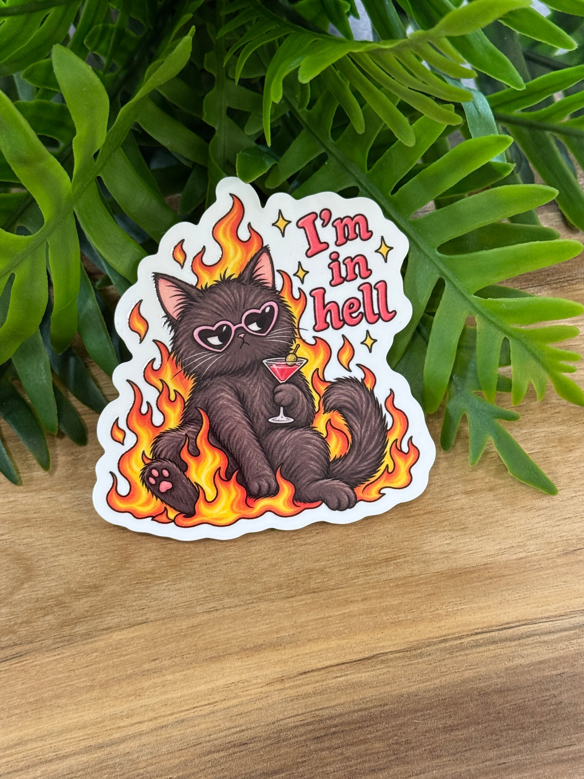 I'm in hell acrylic magnet featuring a dark cat in heart-shaped sunglasses holding a cocktail glass amid orange and yellow flames